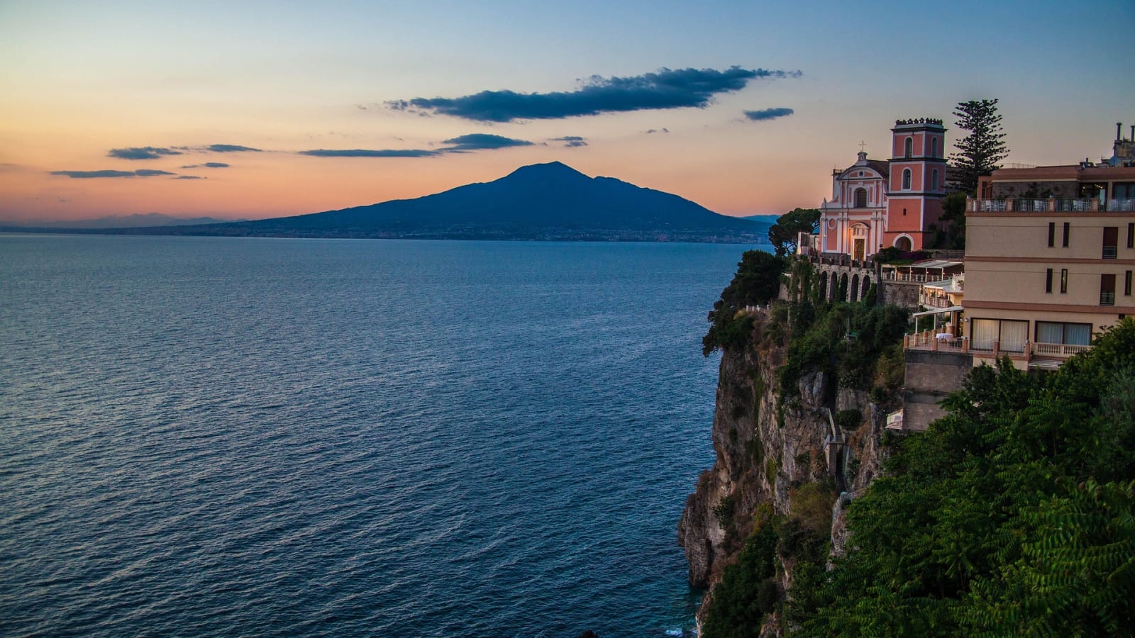 Amalfi Coast cliffside at sunset with Vesuvius on the horizon, Italy
